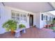 Charming front porch, featuring a stone bench and a dark-stained entry door, all shaded by a carport at 6612 N Orleans Ave, Tampa, FL 33604