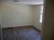 An empty bedroom features wood-look flooring, a window, and neutral colored walls at 8255 Richmond St, Gibsonton, FL 33534