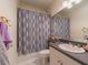 This bathroom features a vanity, sink, toilet and shower/tub combo with a neutral shower curtain at 8304 Aquila St, Port Richey, FL 34668