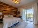 Cozy bedroom featuring a wood accent wall and access to a private balcony with scenic views at 8304 Aquila St, Port Richey, FL 34668