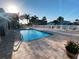 Community swimming pool with lounge chairs, pavers, and lush landscaping on a sunny day with building views at 8304 Aquila St, Port Richey, FL 34668