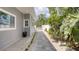 Side exterior shows gray siding with a paved walkway surrounded by well-kept landscaping at 8635 Boca Ciega Dr, St Pete Beach, FL 33706