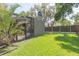 Expansive backyard with well-maintained lawn, screen enclosed lanai, wood fence, and lush landscaping at 9112 Calle Alta, New Port Richey, FL 34655