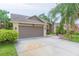 Two-car garage with a brick and beige exterior and well-maintained landscaping at 9112 Calle Alta, New Port Richey, FL 34655
