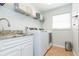 Well-equipped laundry room with modern washer, dryer, sink and storage shelves at 9112 Calle Alta, New Port Richey, FL 34655