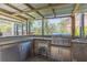 Outdoor kitchen featuring stainless steel grill, prep area, fridge, and stone facade on a covered patio at 9112 Calle Alta, New Port Richey, FL 34655