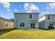 Backyard of the home with a lush lawn extending from the patio, under a bright blue sky with white clouds at 10940 Trailing Vine Dr, Tampa, FL 33610