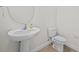 Cozy half bathroom featuring a pedestal sink, toilet, and neutral-colored tile flooring at 10940 Trailing Vine Dr, Tampa, FL 33610