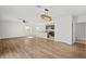 Open-concept living space featuring wood floors, a modern light fixture and a view into the kitchen at 10940 Trailing Vine Dr, Tampa, FL 33610