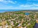 Aerial view of a neighborhood featuring lush trees, lakes, and distant ocean views at 1118 Captains Way, Tarpon Springs, FL 34689