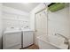 Well-lit laundry room with modern washer and dryer, storage shelves, and utility sink at 1118 Captains Way, Tarpon Springs, FL 34689