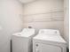 Bright laundry room featuring a white washer and dryer and a wire shelf for storage at 15306 Broad Brush Dr, Sun City Center, FL 33573