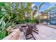Inviting backyard with a stone fire pit area, lush greenery, and view of the pool enclosure at 15507 Avocetview Ct, Lithia, FL 33547