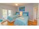 Bright bedroom featuring two twin beds with blue comforters, art, and access to the patio at 216 Pine Ave # R, Anna Maria, FL 34216