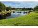 Scenic pond view surrounded by lush green grass and tropical palm trees in a serene community setting at 225 Country Club Dr # A207, Largo, FL 33771
