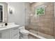 Bright bathroom featuring a white vanity, toilet, and a tiled glass-enclosed shower with a window offering natural light at 2402 W Parkland Blvd, Tampa, FL 33609