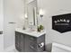 Modern bathroom vanity with dark gray cabinets, white countertop and a large mirror with decorative lighting at 2402 W Parkland Blvd, Tampa, FL 33609