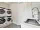 Modern laundry room featuring stacked washer and dryer units and a stainless steel sink with a pull-down faucet at 2402 W Parkland Blvd, Tampa, FL 33609
