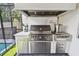 Outdoor kitchen features a built-in grill, marble backsplash, stainless steel storage and tile flooring at 2402 W Parkland Blvd, Tampa, FL 33609