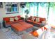 Relax on this cozy patio, featuring orange couches, ottoman tables, and floral accents at 2460 Beacon Groves Blvd, Palm Harbor, FL 34683