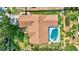 Aerial view of house with a backyard pool with pool toys and brown roof at 3122 Lake Valencia E Ln, Palm Harbor, FL 34684