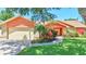 Inviting single-story home with an attached two-car garage and a beautifully landscaped yard at 3122 Lake Valencia E Ln, Palm Harbor, FL 34684