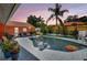 Backyard pool featuring an orange house, pool inflatables, and several trees and plants at 3122 Lake Valencia E Ln, Palm Harbor, FL 34684