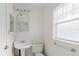 Bright all-white bathroom featuring a pedestal sink, toilet, and ample lighting at 3139 Corona Dr, Holiday, FL 34690