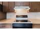 Close-up of the kitchen featuring a smooth-top range, wooden cabinets, and neutral countertops at 3139 Corona Dr, Holiday, FL 34690