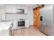 Well-lit kitchen with stainless steel appliances, white cabinets and wood sliding barn door at 3445 Briar Cliff Dr, Holiday, FL 34691