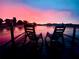 A serene sunset over a tranquil lake, viewed from a private dock with rocking chairs at 3629 Lake Breeze Dr, Land O Lakes, FL 34639