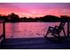 Beautiful pink sunset over a lake with a rocking chair sitting on the edge of a wooden dock at 3629 Lake Breeze Dr, Land O Lakes, FL 34639