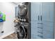 Modern laundry room with stacked washer and dryer and stylish blue cabinets at 3629 Lake Breeze Dr, Land O Lakes, FL 34639
