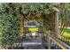 View of a trellis covered in flowering vines with rocking chairs, and a view of the lawn at 3629 Lake Breeze Dr, Land O Lakes, FL 34639