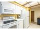 Bright kitchen featuring white appliances, white cabinets, laminate countertops and a yellow accent wall at 4442 Summer Oak Dr, Tampa, FL 33618