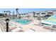 Community swimming pool with multiple lounge chairs and umbrellas, surrounded by tropical landscaping and community building at 5216 81St N St # 2, St Petersburg, FL 33709