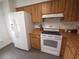 Efficient kitchen layout with white refrigerator, matching range, and warm wood cabinetry at 612 Bryan Terrace Dr, Brandon, FL 33511