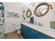 Nautical-themed bathroom featuring a double vanity with blue cabinets, mirrors, and unique decor at 6511 Georgia Ave, Bradenton, FL 34207