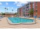 Community pool and sundeck with lounge chairs in front of a low-rise residential building with palm trees on a sunny day at 6800 20Th N Ave # 307, St Petersburg, FL 33710