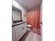 Modern bathroom with granite countertops, white cabinets, and an orange floral shower curtain at 6942 Ripple Pond Loop, Zephyrhills, FL 33541