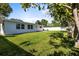 Green backyard features a lush lawn, mature trees, flower pots, and an updated painted white house at 722 61St S Ave, St Petersburg, FL 33705