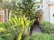 Inviting front entrance with a red door, decorative wreath, seating, and beautiful landscaping at 7704 Tuscany Woods Dr, Tampa, FL 33647