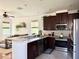 Open kitchen with dark wood cabinetry, stainless steel appliances, and a breakfast bar overlooking the living area at 7704 Tuscany Woods Dr, Tampa, FL 33647