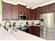 Well-lit kitchen with stainless steel appliances, dark cabinets, and granite countertops at 7704 Tuscany Woods Dr, Tampa, FL 33647