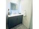 Bathroom vanity with gray cabinets, marble top, and lighted mirror at 8050 Roxburgh Ct, Weeki Wachee, FL 34613