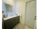 Bathroom with a stylish gray vanity, marble top, and lighted mirror at 8050 Roxburgh Ct, Weeki Wachee, FL 34613