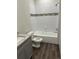 Bathroom featuring a shower-tub combo, patterned tile accent, gray vanity, and wood-look floors at 8149 Cashew, Webster, FL 33597