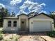 Inviting single-story home featuring a two-car garage and a covered front entrance, set against a bright, partly cloudy sky at 8149 Cashew, Webster, FL 33597