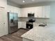 Modern kitchen featuring white cabinets, granite countertops, stainless steel appliances, and hardwood floors at 8149 Cashew, Webster, FL 33597