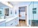Bathroom featuring double sinks, a glass shower, a large mirror, and an entrance to the bedroom at 9304 Lake Chase Island Way, Tampa, FL 33626